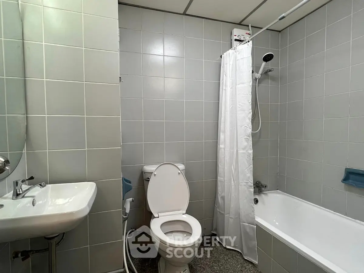 Modern bathroom with bathtub and shower in a sleek tiled setting.
