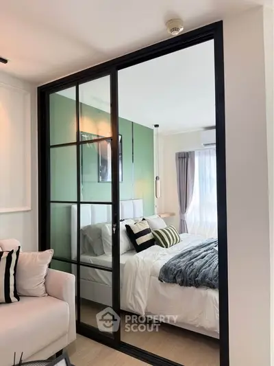 Modern bedroom with glass partition and stylish decor in a cozy apartment.