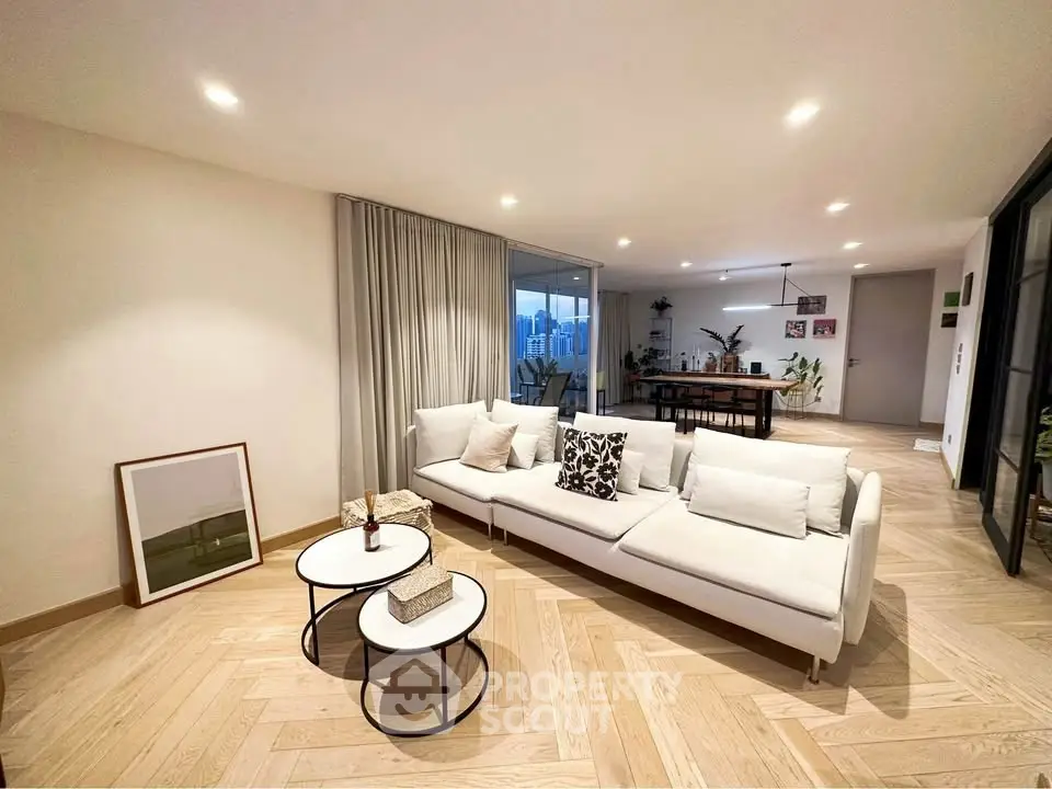 Spacious modern living room with elegant decor and open layout, featuring a cozy white sofa and stylish coffee tables.