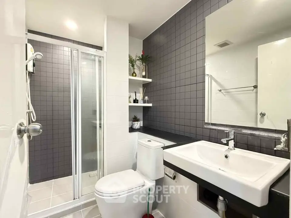 Modern bathroom with sleek design, featuring a glass shower, white fixtures, and stylish tile accents.
