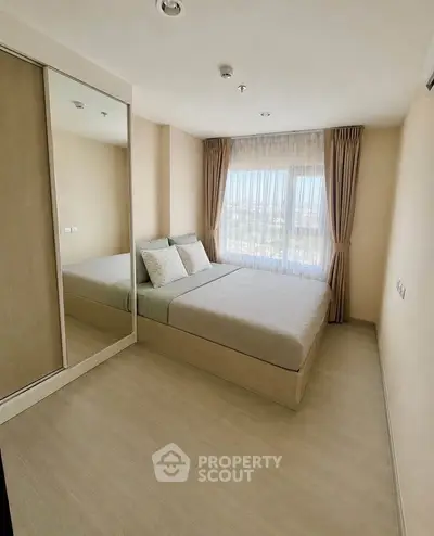 Modern bedroom with large window and mirrored wardrobe in a cozy apartment.