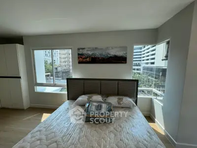 Modern bedroom with large windows and city view, featuring stylish decor and natural light.