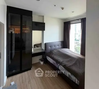 Modern bedroom with large window and sleek black wardrobe in urban apartment