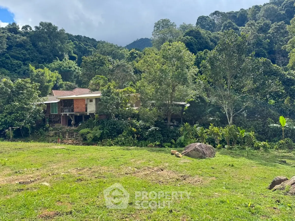 Charming secluded house nestled in lush greenery with mountain backdrop, perfect for nature lovers seeking tranquility.
