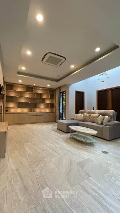 Spacious modern living room with elegant lighting and built-in shelving, perfect for stylish living.