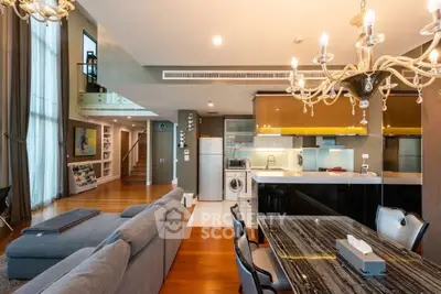 Luxurious open-plan living room and kitchen with elegant chandeliers and modern appliances.