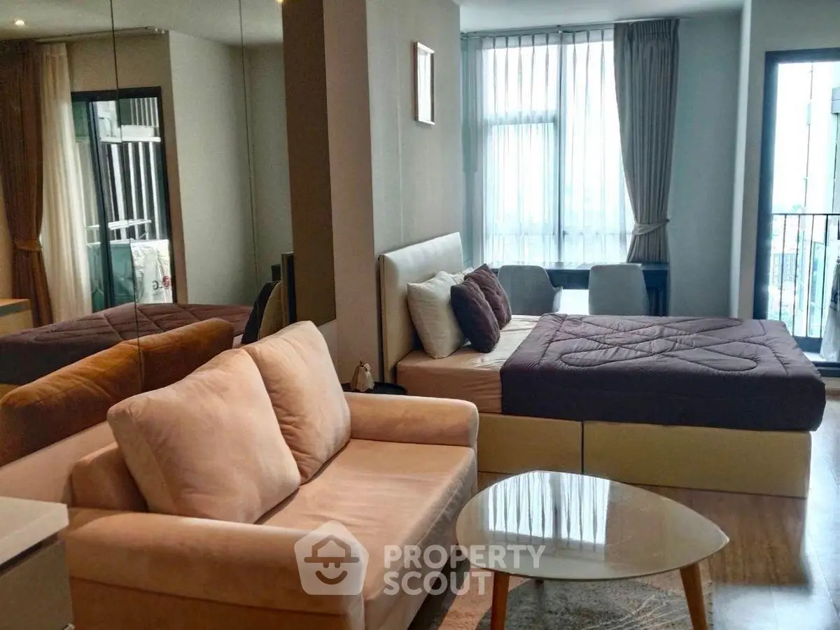 Modern studio apartment with cozy living area and large windows