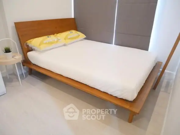 Modern bedroom with minimalist wooden bed and stylish decor.