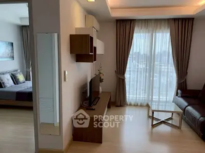 Modern living room with stylish decor and natural light, featuring a cozy bedroom view.