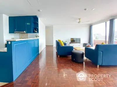 Spacious living room with blue accents and wooden flooring, featuring modern furniture and natural light.