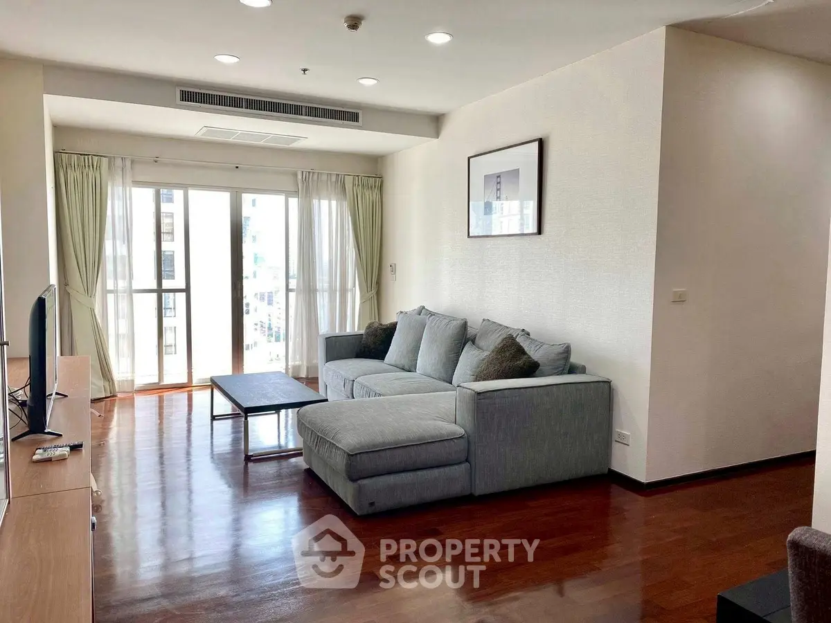Spacious living room with modern sofa and natural light from large windows.