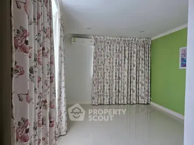 Spacious room with floral curtains and green accent wall, perfect for creative interior design.