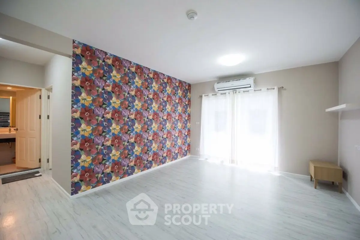 Spacious living room with vibrant floral accent wall and natural light