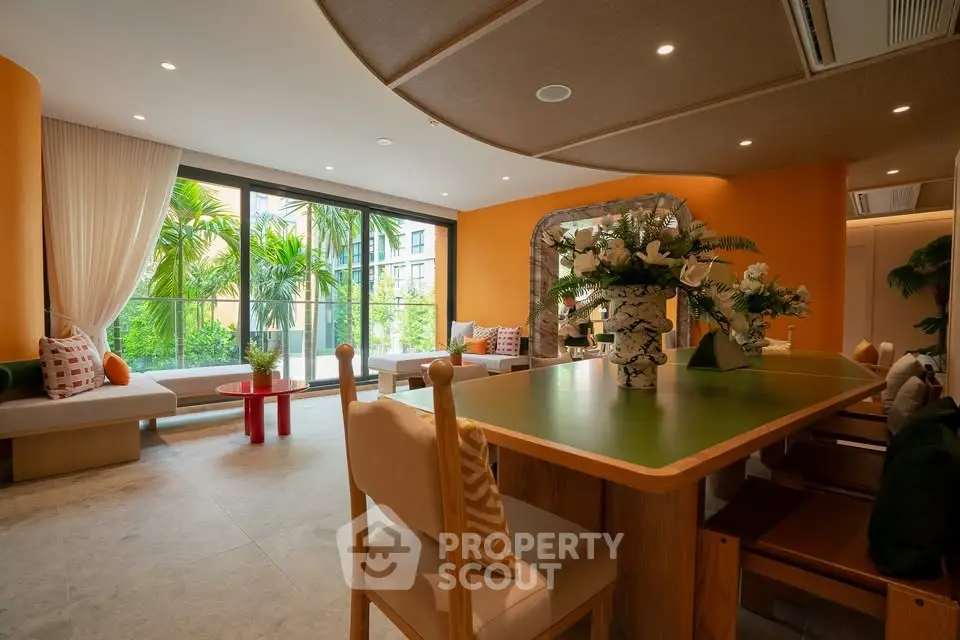 Spacious living room with modern decor and large windows overlooking lush greenery.