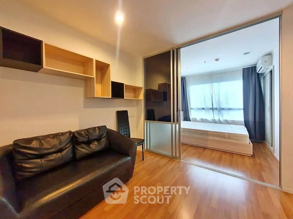 Modern apartment with cozy living room and spacious bedroom separated by sliding glass doors.