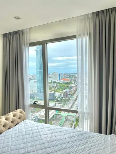 Luxurious bedroom with stunning city view from high-rise window.