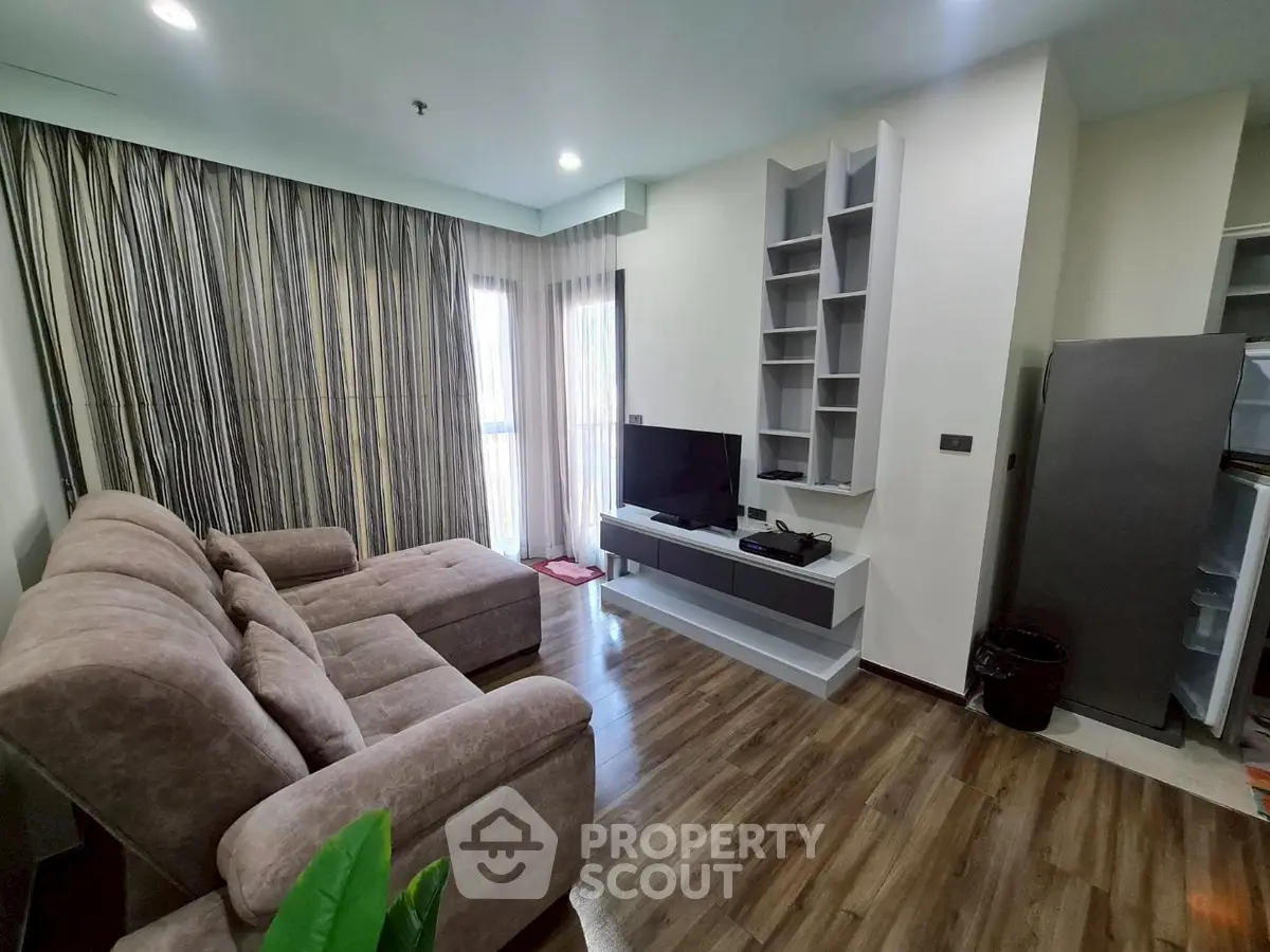 Modern living room with cozy sofa and entertainment center, featuring stylish curtains and wooden flooring.