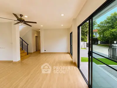 Spacious living room with wooden flooring and large sliding glass doors opening to a garden view.