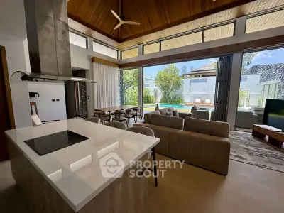 Luxurious open-plan living room with pool view and modern kitchen in a tropical villa.