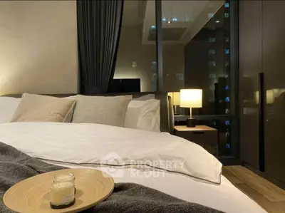 Luxurious bedroom with city view, cozy bedding, and ambient lighting.