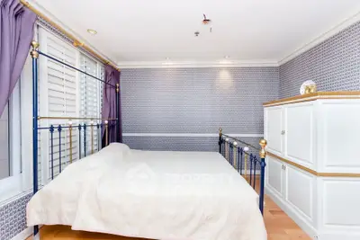 Elegant bedroom with stylish decor and natural light, featuring a classic bed and ample storage space.