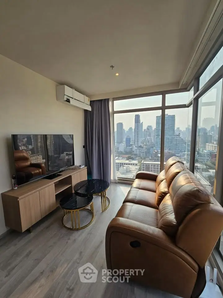 Modern living room with city view, leather sofa, and sleek TV setup.