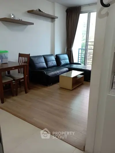 Cozy living room with modern furniture and natural light from balcony.