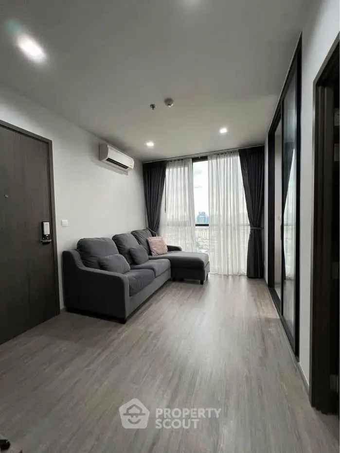 Modern living room with sleek design and large windows offering natural light and city views.