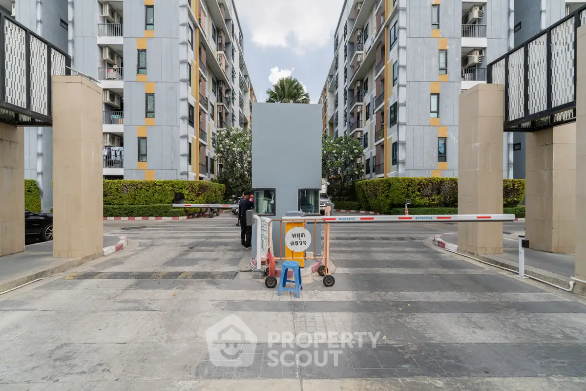 Modern apartment complex entrance with security booth and barrier gate