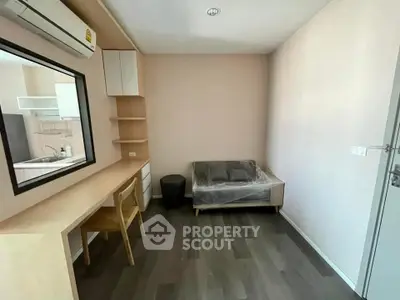 Modern study room with desk, chair, and sofa in a minimalist apartment setting.