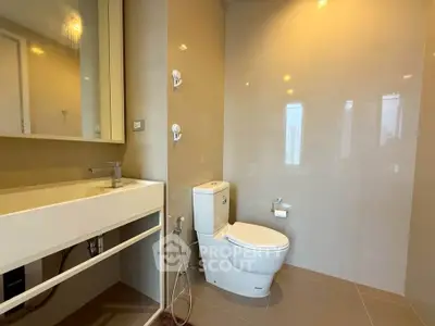 Modern bathroom with sleek fixtures and neutral tones, featuring a toilet and stylish sink area.