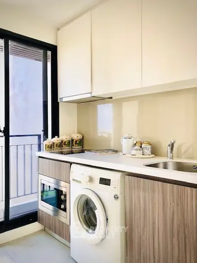 Modern kitchen with washing machine and sleek cabinetry in bright apartment