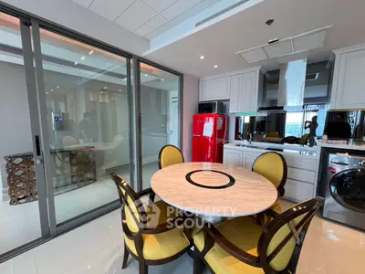 Modern kitchen with dining area, red fridge, and washing machine in sleek apartment.