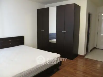 Spacious bedroom with modern dark wood furniture and hardwood flooring.