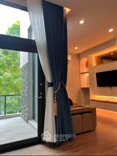 Luxurious living room with floor-to-ceiling windows and elegant curtains, opening to a serene balcony view.