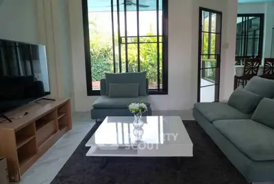 Stylish living room with modern furniture and large windows offering lush garden views.