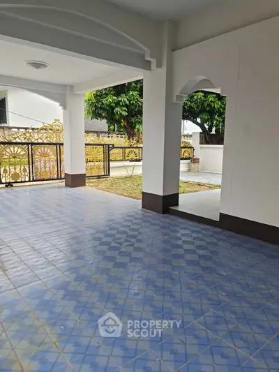 Spacious covered patio with decorative ironwork and tiled flooring, perfect for outdoor relaxation.