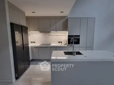 Modern kitchen with sleek cabinetry and island sink in contemporary home.