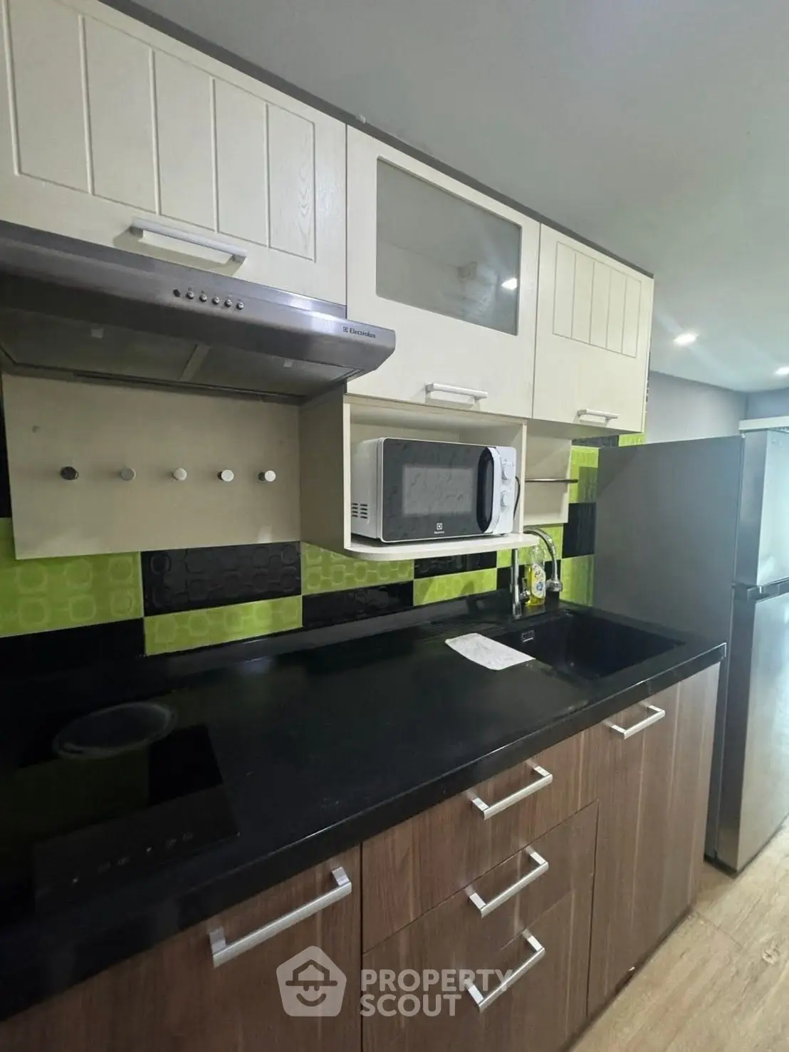 Modern kitchen with sleek cabinetry and appliances, featuring a microwave and stylish backsplash.