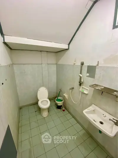 Compact bathroom with basic fixtures and sloped ceiling