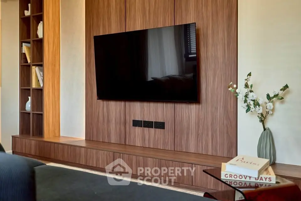 Modern living room with sleek wooden paneling and mounted TV, perfect for entertainment.