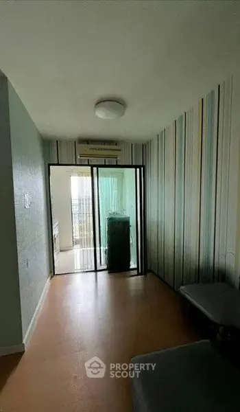 Cozy room with sliding glass doors leading to a balcony, featuring modern striped wallpaper and air conditioning.