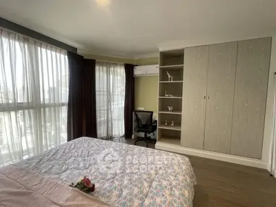 Spacious bedroom with large windows and modern furnishings in a high-rise apartment.