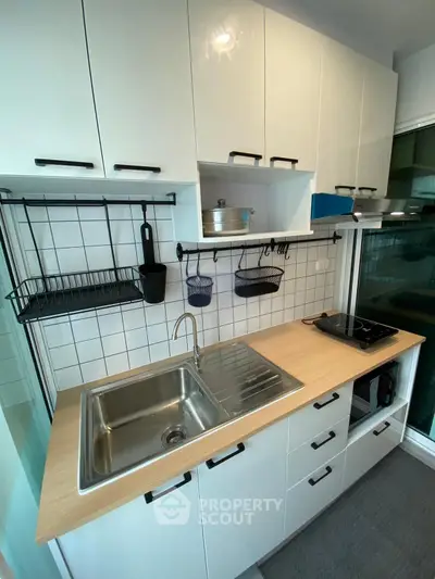 Modern kitchen with sleek cabinetry and stainless steel sink in compact layout.