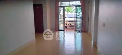 Spacious interior with tiled flooring and large windows leading to a driveway.