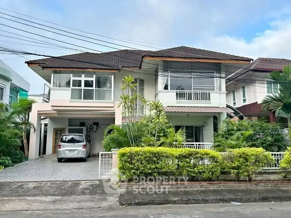 Spacious two-story house with lush greenery and driveway in a serene neighborhood.