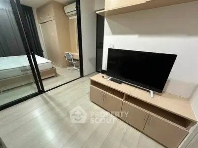 Modern apartment interior with bedroom and living area featuring sleek furniture and a flat-screen TV.