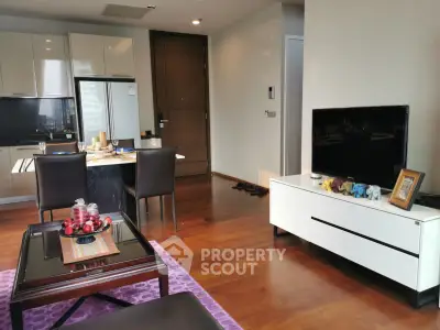 Modern living room with sleek furniture and open kitchen layout, featuring hardwood floors and stylish decor.