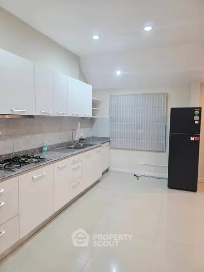 Modern kitchen with sleek cabinets, granite countertops, and gas stove in a spacious layout.