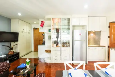 Bright and modern living room with open kitchen, featuring sleek cabinetry and stylish decor.